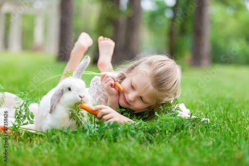 Little girl playing with white rabbit outdoor