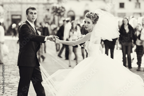 Bride whirls on the street holding groom's hand