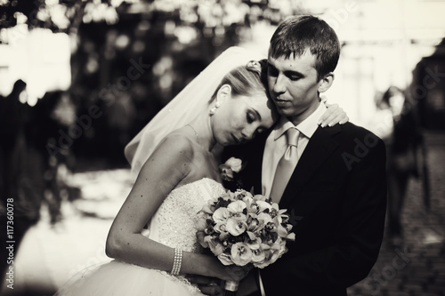 Bride leans to groom's shoulder while he hugs her tender somewhw