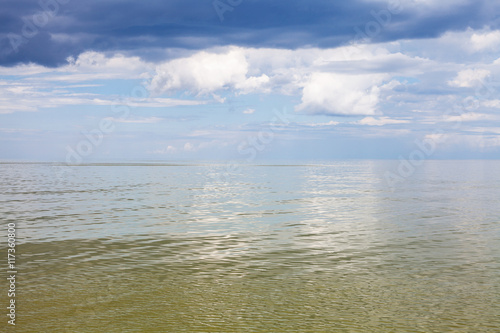 calm green water of Azov Sea and cloudy sky
