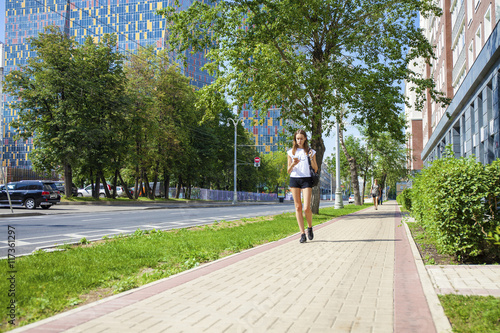 Young beautiful woman in black short walking on the summer stree