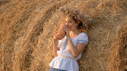young beautiful girl is drinking milk from a jug on the nature