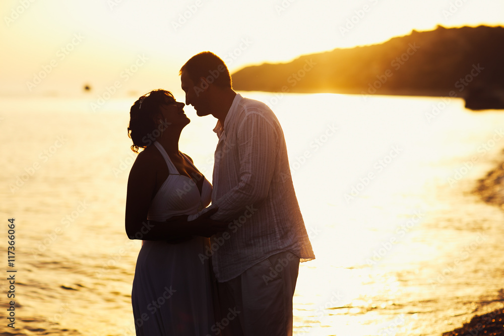 Groom hold each other tightly standing on the sea shore in the l