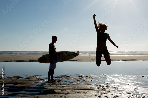 happy woman jumping in sea beach sunset silhouette. holiday vacation concept.