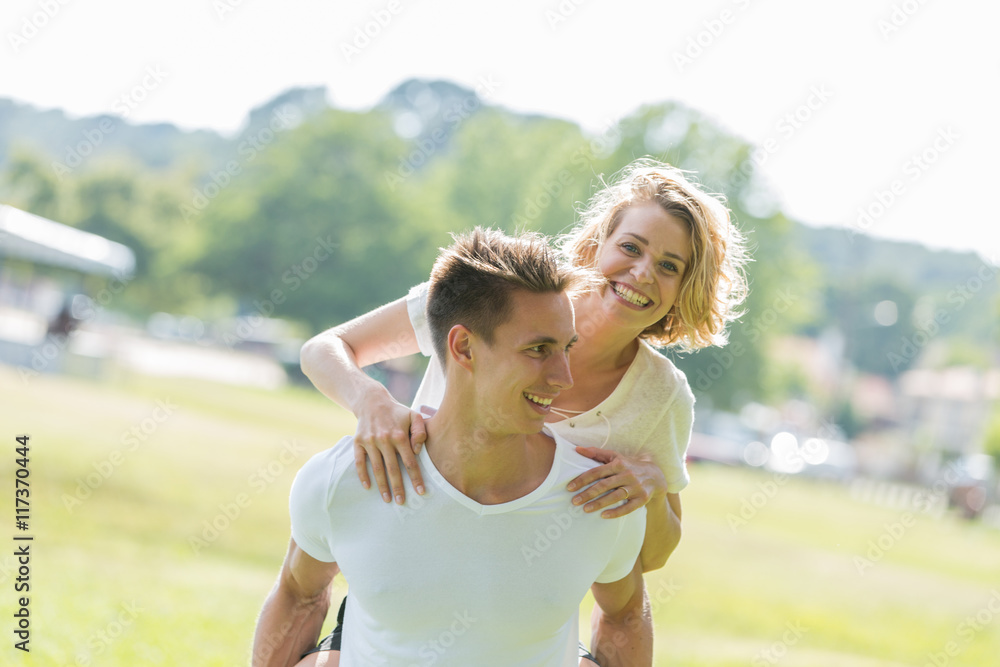 Man giving piggyback ride- carrying on the back his girlfriend Man giving piggyback ride- carrying on the back his girlfriend