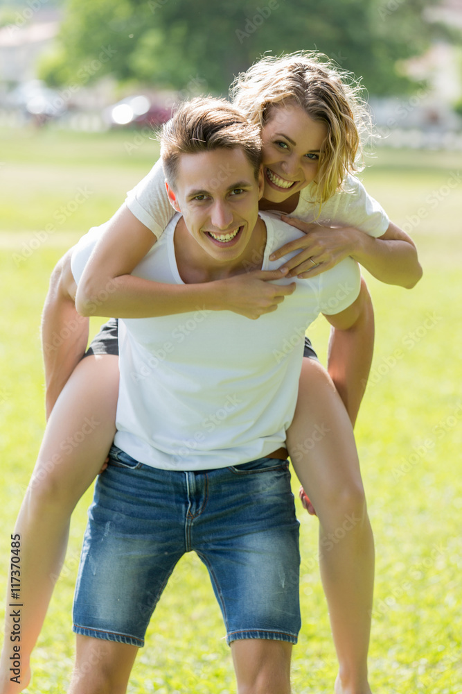 Obraz premium Man giving piggyback ride- carrying on the back his girlfriend