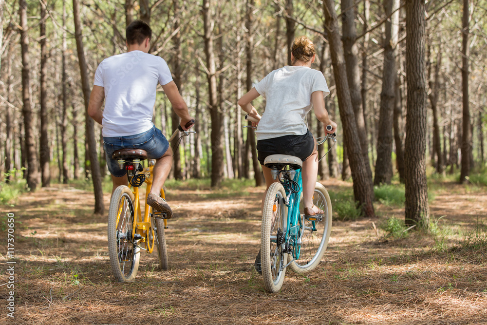 Fototapeta premium couple of cyclists riding bicycles on sunny summer day