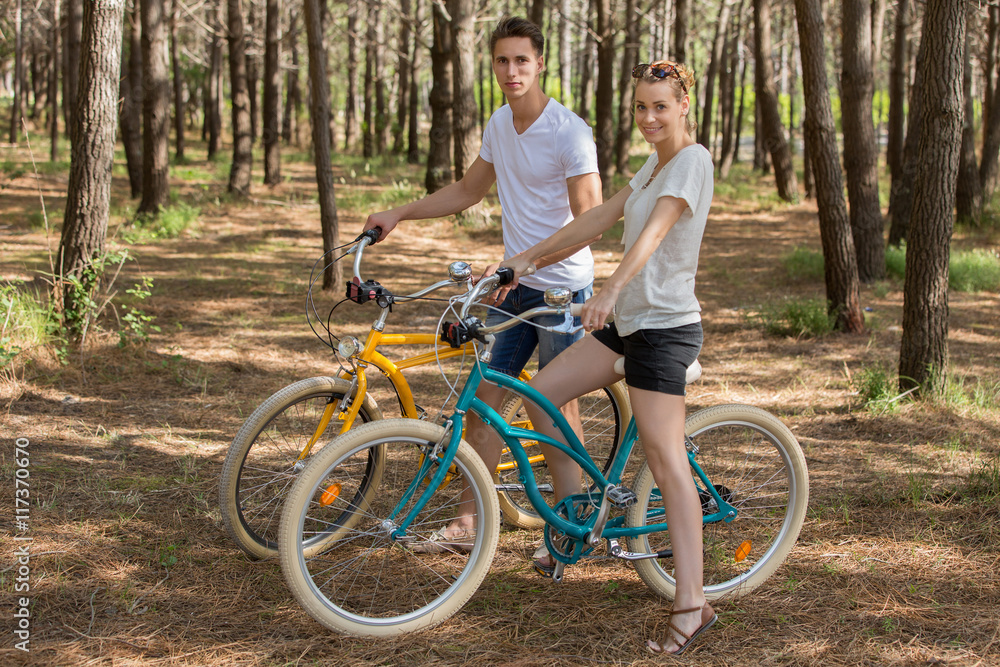 Fototapeta premium couple of cyclists riding bicycles on sunny summer day
