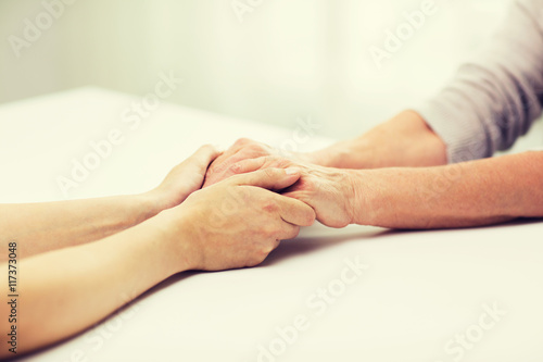 close up of senior and young woman holding hands