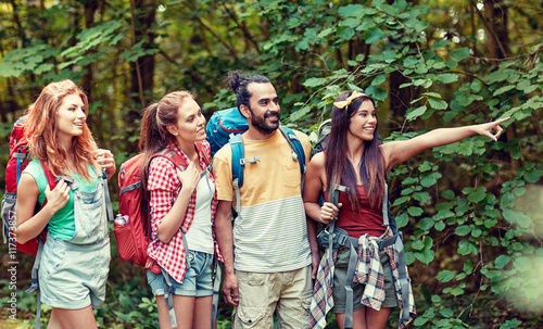 group of smiling friends with backpacks hiking