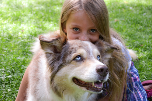 blondes Mädchen umarmt Australian Shepherd