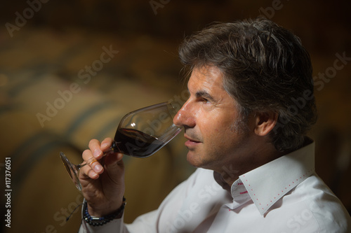 Portrait confidant vintner drinking red wine in winery