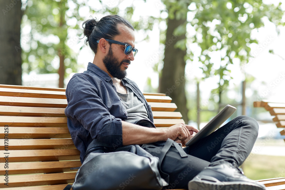Obraz premium man with tablet pc sitting on city street bench