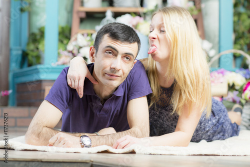 Young married couple lying on the blanket. The woman shown tongue in the direction of men.