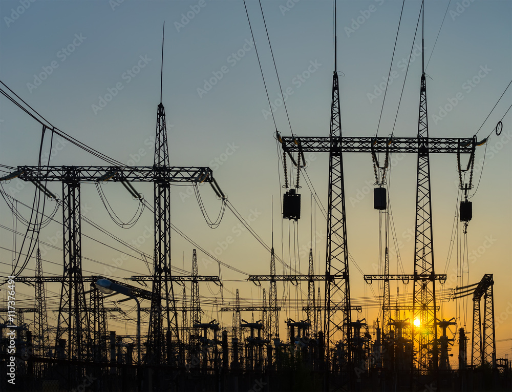 silhouette of high voltage power lines with transformers at suns