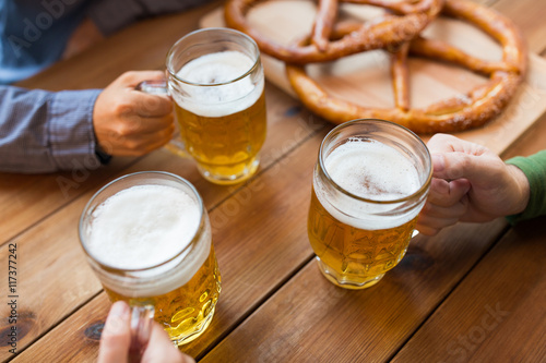 close up of hands with beer mugs at bar or pub