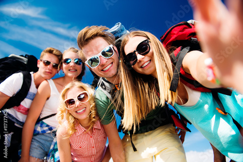 Teenagers with backpacks taking selfie, summer festival photo