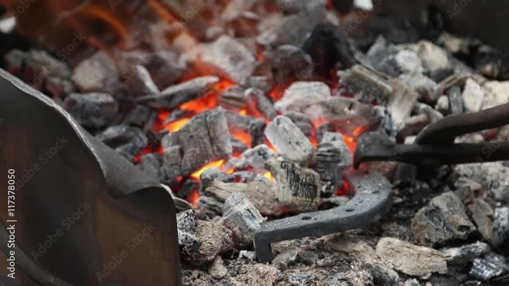 Blacksmith corrects coals in a Brazier and harassing fire from the Horseshoe Blacksmith corrects coals in a Brazier and harassing fire from the Horseshoe