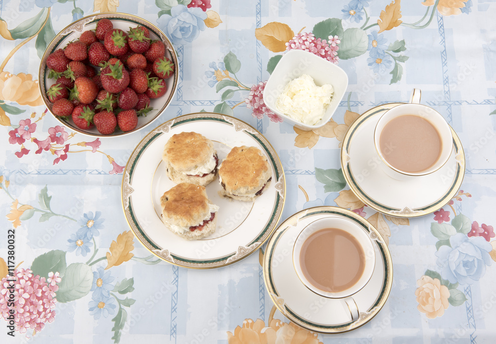 Image of scones with cream, tea and strawberries on a table Image of scones with cream, tea and strawberries on a table