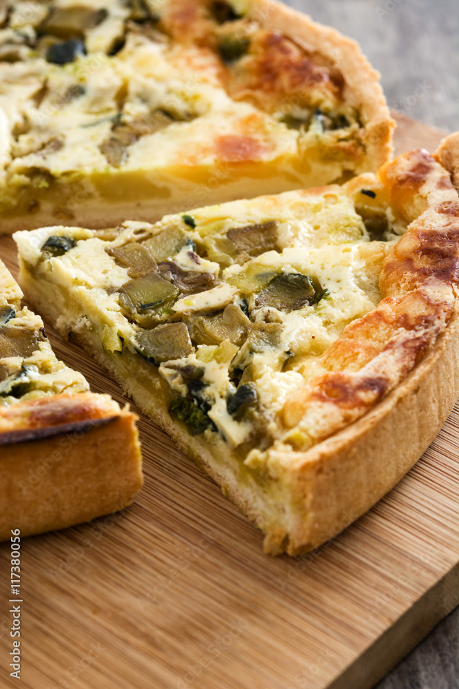 French quiche Lorraine with vegetables on a rustic wooden table


