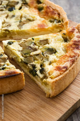 French quiche Lorraine with vegetables on a rustic wooden table