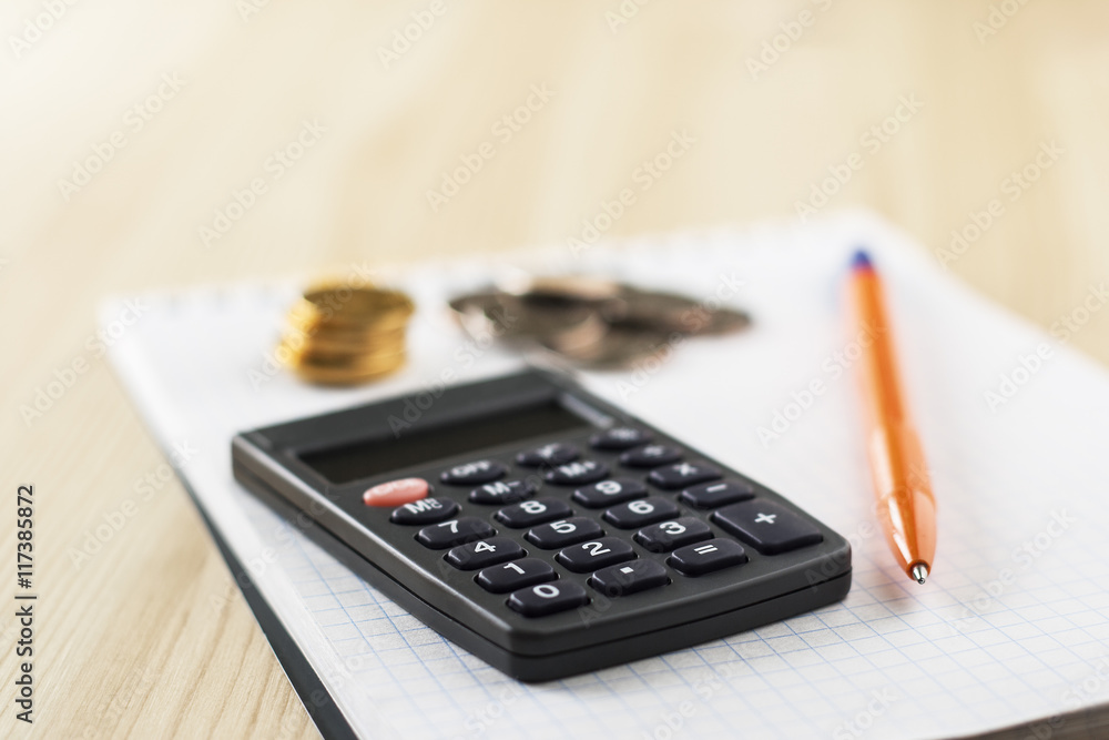 Calculator, pen, coins lie on notebook. Counting money. Calculator, pen, coins lie on notebook. Counting money.