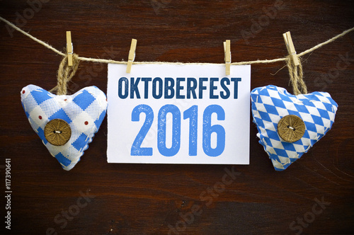 Schild mit Oktoberfest 2016 mit Bretzeln, Bayernfahne, Bierkrug und Lebkuchenherz 