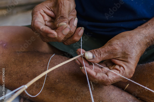 Old man tying a rope for make a kite.