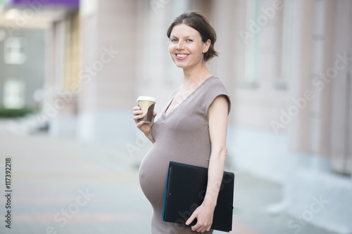 Active mom. Portrait of happy young business pregnant woman looking at camera while standing on the street with document folder. Smiling future mom working on her late pregnancy period Free Download Active mom. Portrait of happy young business pregnant woman looking at camera while standing on the street with document folder. Smiling future mom working on her late pregnancy period - GFXLoad