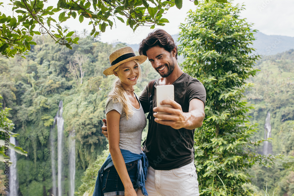 Couple taking selfie with waterfall in background