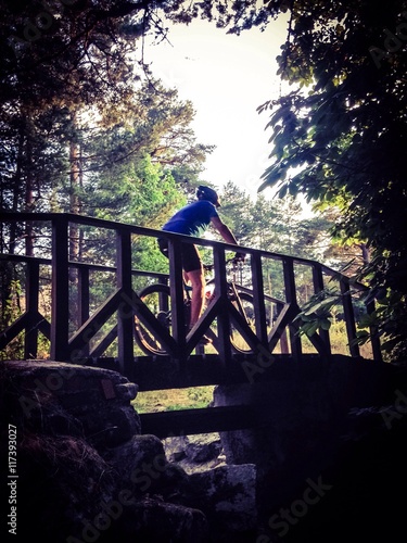 Ciclista cruzando un puente dentro del bosque photo