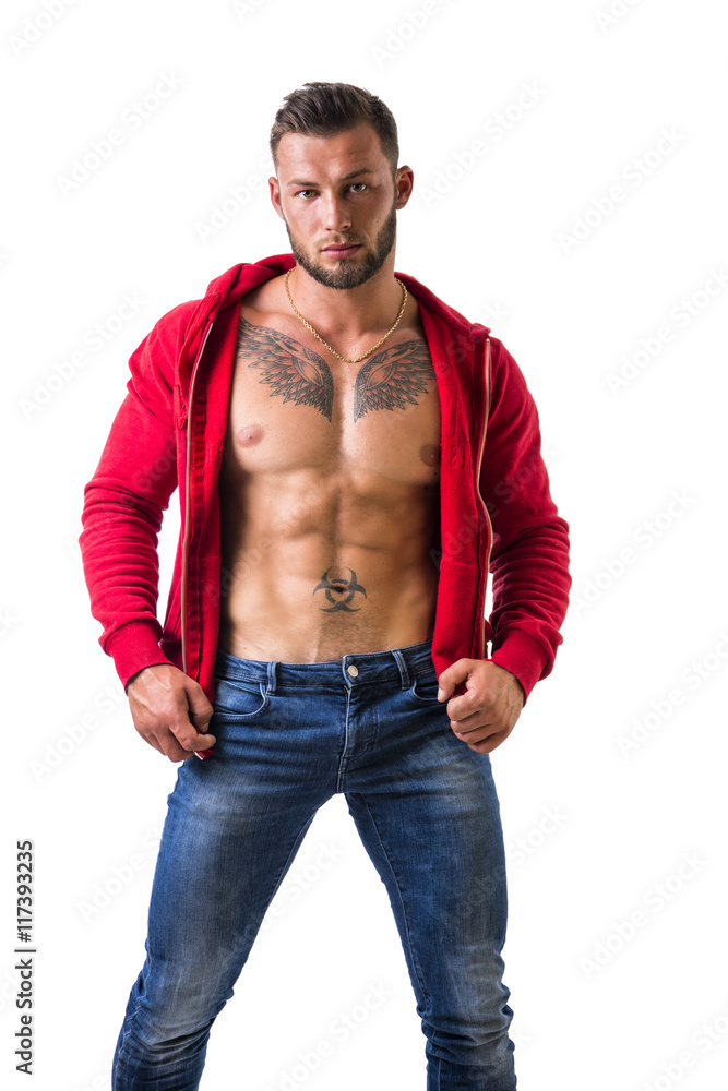 Fototapeta premium Handsome muscular man with sweater open on naked torso, standing, isolated on white background in studio shot