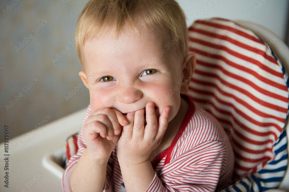Smiling boy sits and climbs fingers in her mouth Smiling boy sits and climbs fingers in her mouth