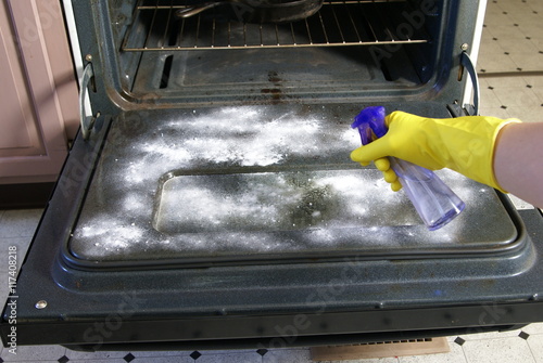 Natural Oven Cleaning. Spraying water onto baking soda powder for cleaning.