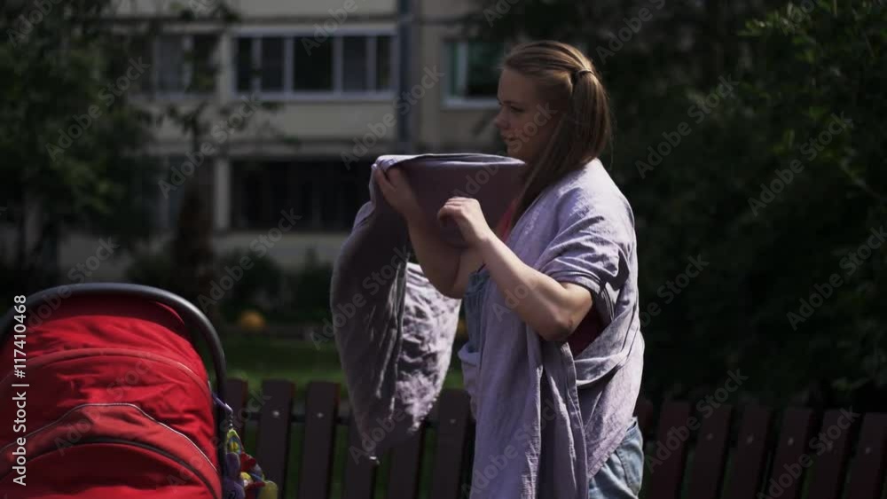 Young mother put on baby sling take little child from carriage. Summer day. Motherhood. Young mother put on baby sling take little child from carriage. Summer day. Motherhood.