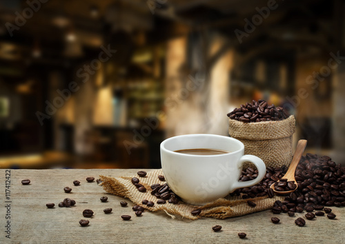 Hot Coffee cup with Coffee beans on the wooden table and the cof