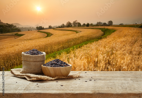 Black Rice in bowl and burlap sack on wooden table with the gold