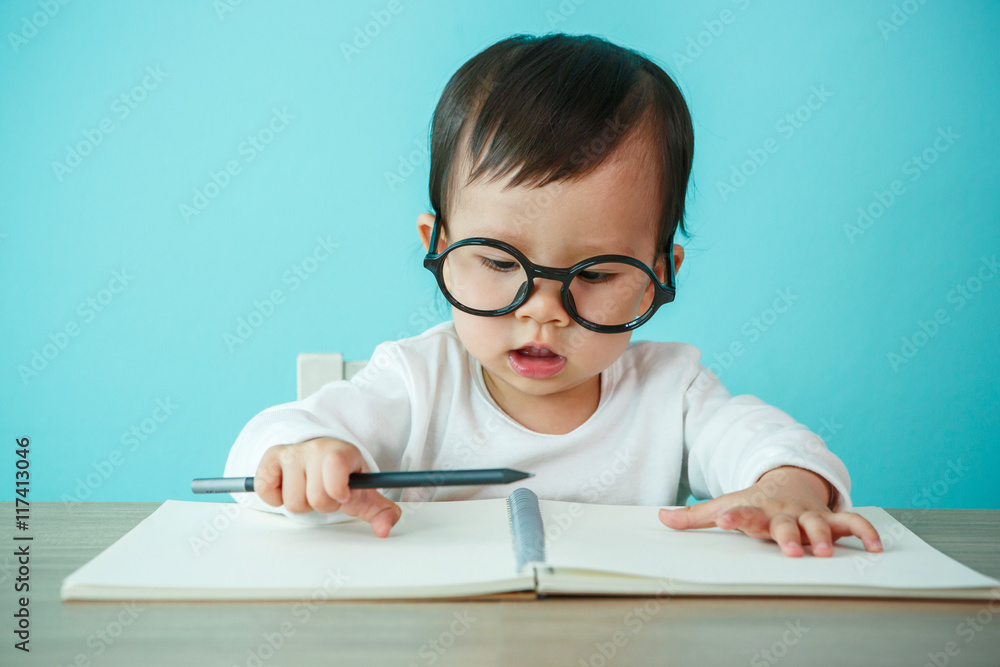 Newborn smiling wearing glasses, on the table (soft focus on the
