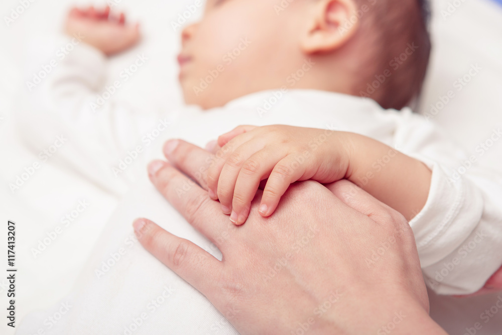 Hand the sleeping baby in the hand of mother close-up (Soft focu