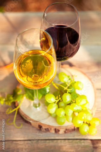Green grapes and two glasses of the white and red wine on the vi