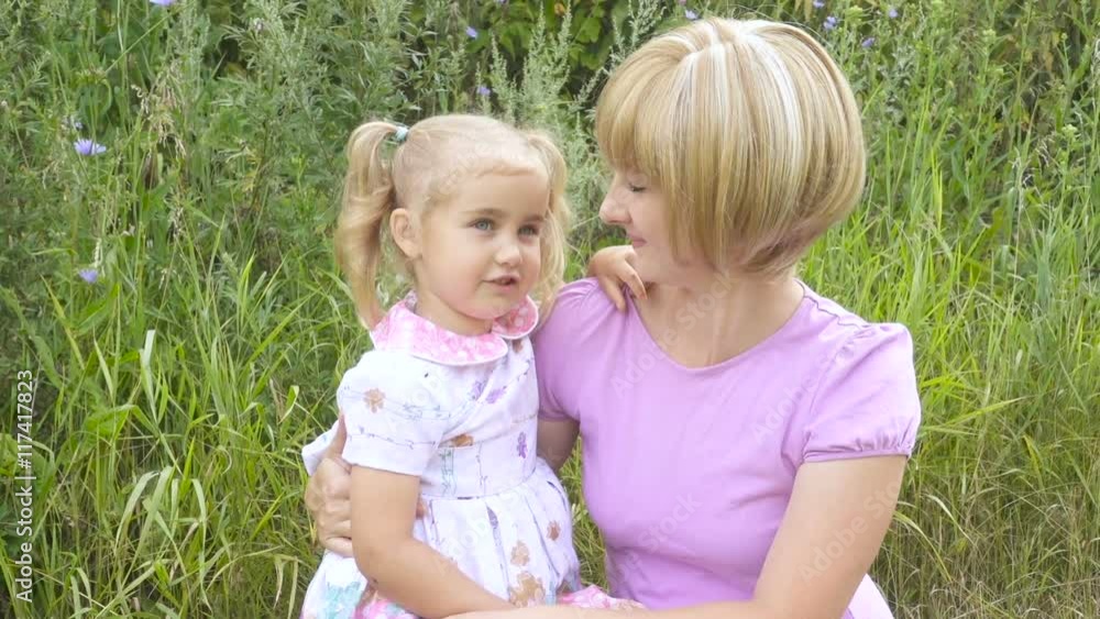 Young mother talks with a little daughter hugging her. Young mother talks with a little daughter hugging her.