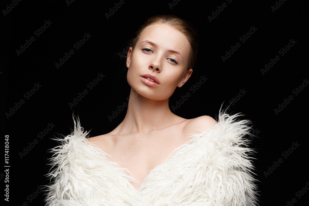 A sensual beautiful young woman with nude makeup on her perfect glowing face wearing fashionable white artificial fur coat on the naked body is posing in the studio A sensual beautiful young woman with nude makeup on her perfect glowing face wearing fashionable white artificial fur coat on the naked body is posing in the studio