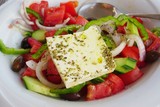 A Greek salad with a slab of feta cheese on top