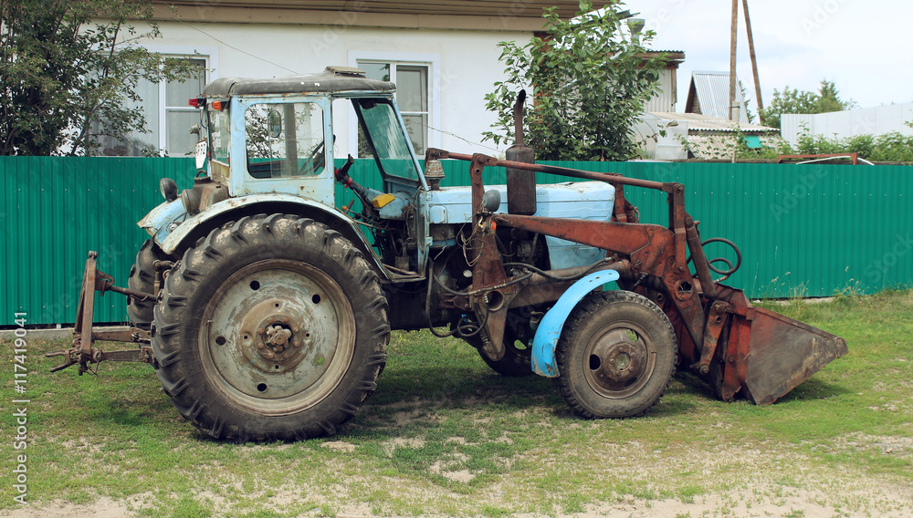 Old excavator near a house in the village