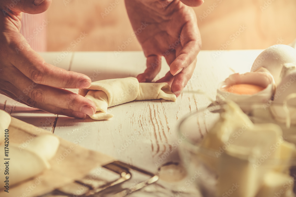 Baker making croissants on rustic wood background Baker making croissants on rustic wood background