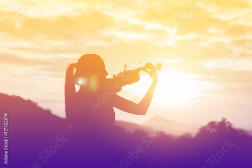 Silhouette women play violin sunset background