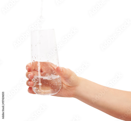 Water pouring into full drinking glass in woman's hand
