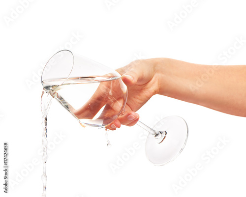 Water pouring from full wine glass in woman's hand