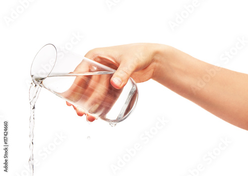Water pouring from full drinking glass in woman's hand