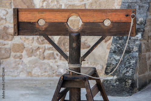 Photography Old pillory on castle stone wall background